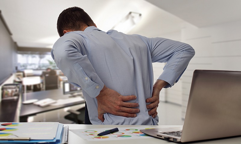 Business man with back pain sin an office . Pain relief concept