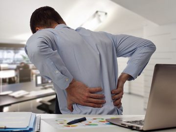 Business man with back pain sin an office . Pain relief concept